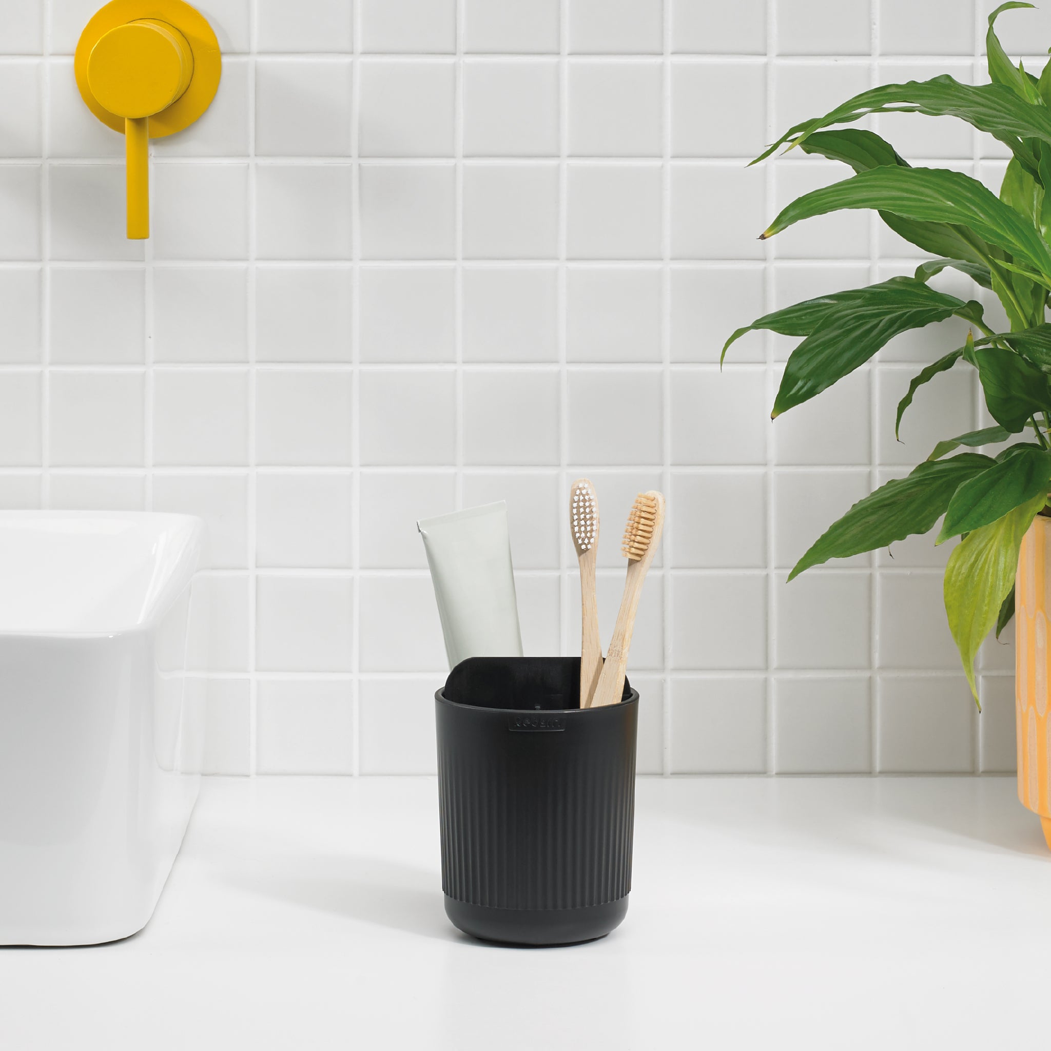 Black ribbed toothbrush holder, modern and minimalist, keeps counters clutter-free and stylish.
