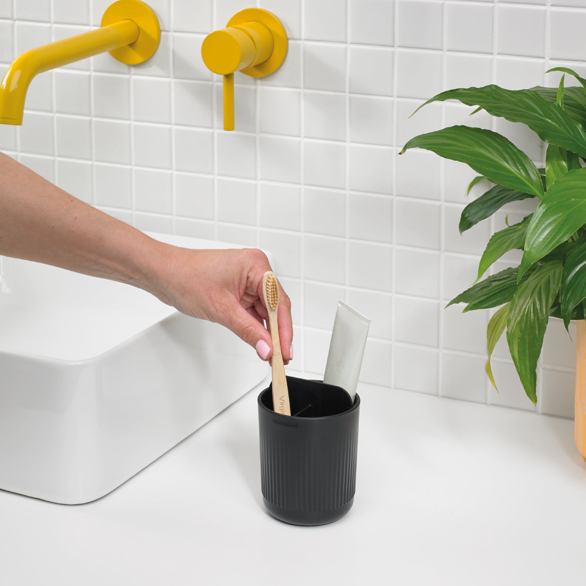 Black ribbed toothbrush holder, sleek and modern, keeps brushes and toothpaste organized stylishly.