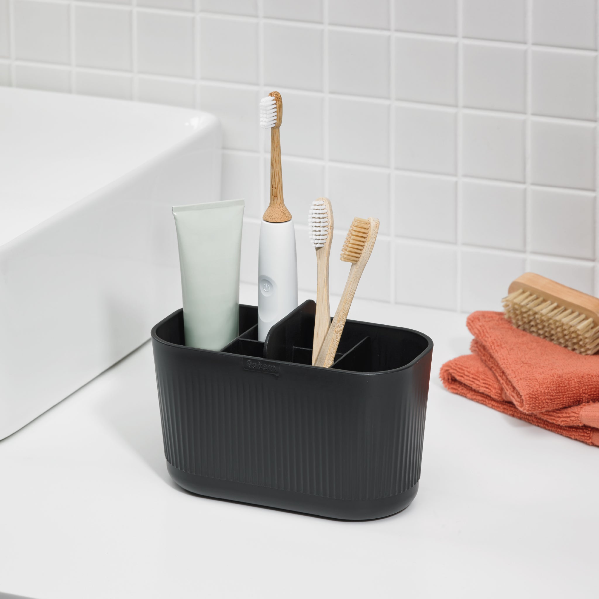 Black bathroom caddy with ribbed design, ideal for organizing toothbrushes, toothpaste, and essentials.