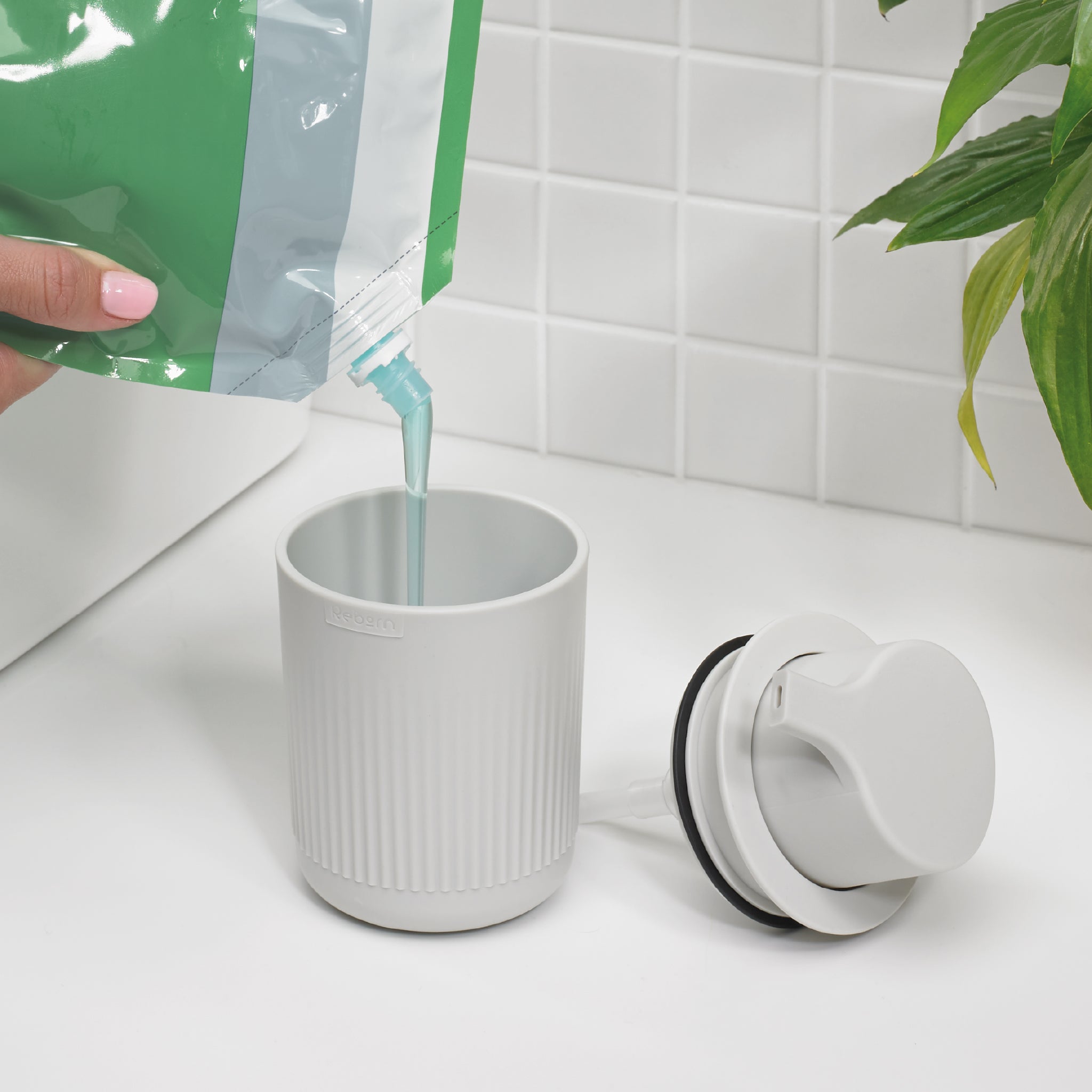 Refillable ribbed soap dispenser in light gray, modern design reduces plastic waste elegantly.