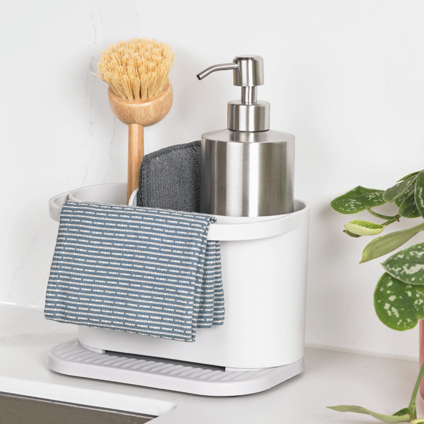Recycled kitchen sink tidy with bamboo brush, soap dispenser, and cloth storage for an organized, eco-friendly sink.