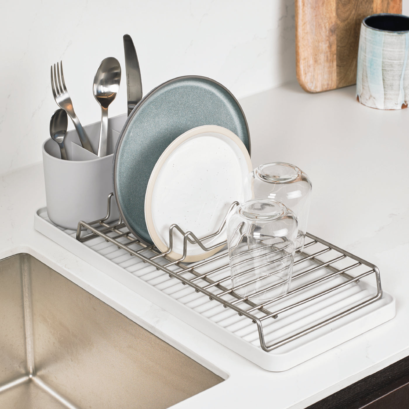 Compact recycled dish drying rack with sturdy metal frame, efficient drainage, and cutlery holder.