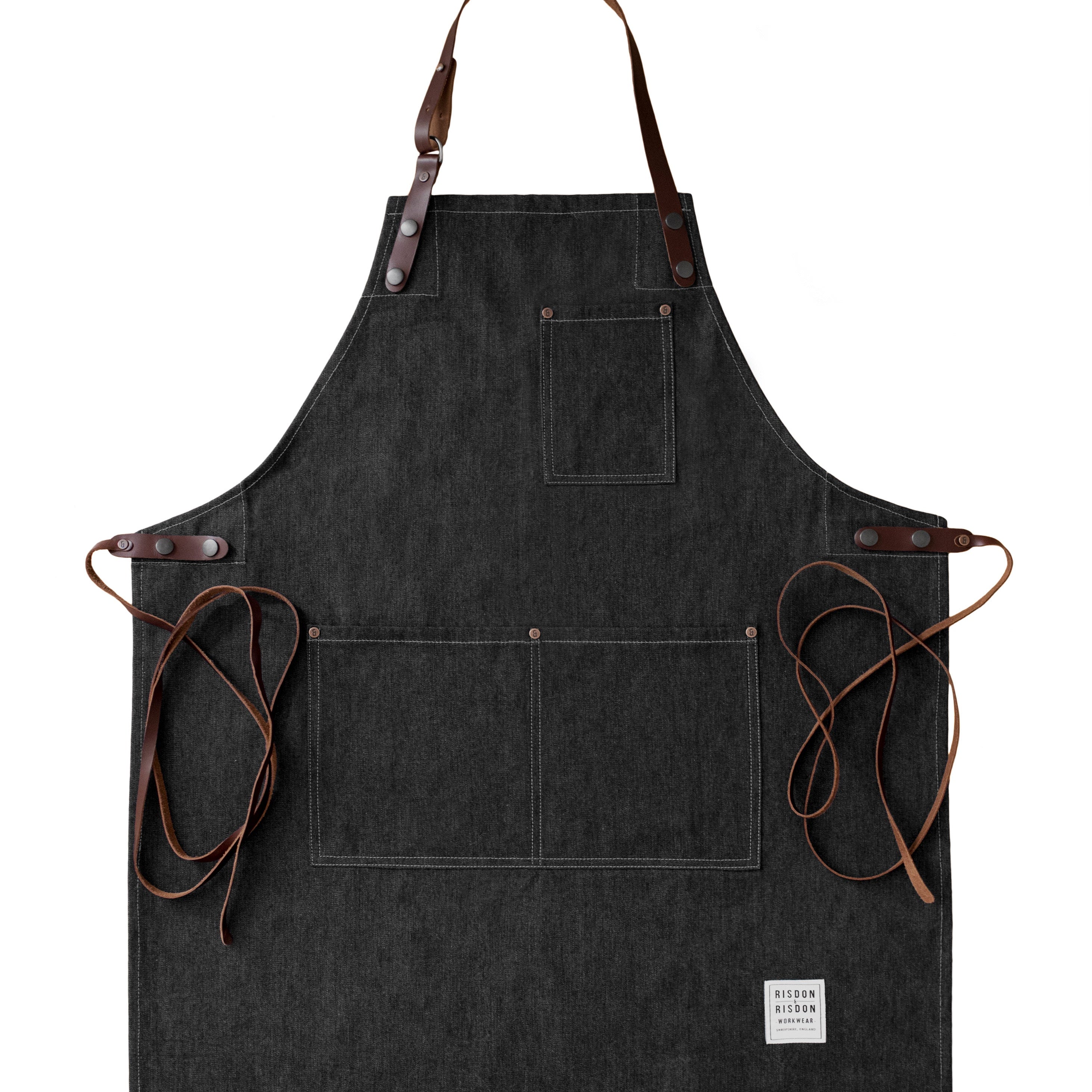 Handcrafted, black, denim apron; made in Britain with pockets and removable leather straps.